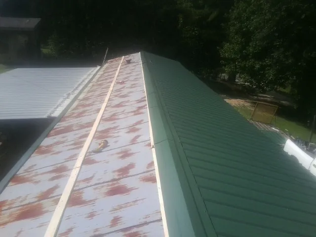 Old rusted panels beside newly installed green metal roofing — Wind Damage Roof Repair by Roofing Brothers in Davis