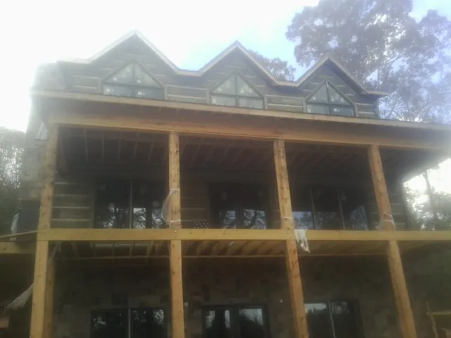 Dormers and porch framing on a large log home under construction — Roof Coating work by our crew in Davis